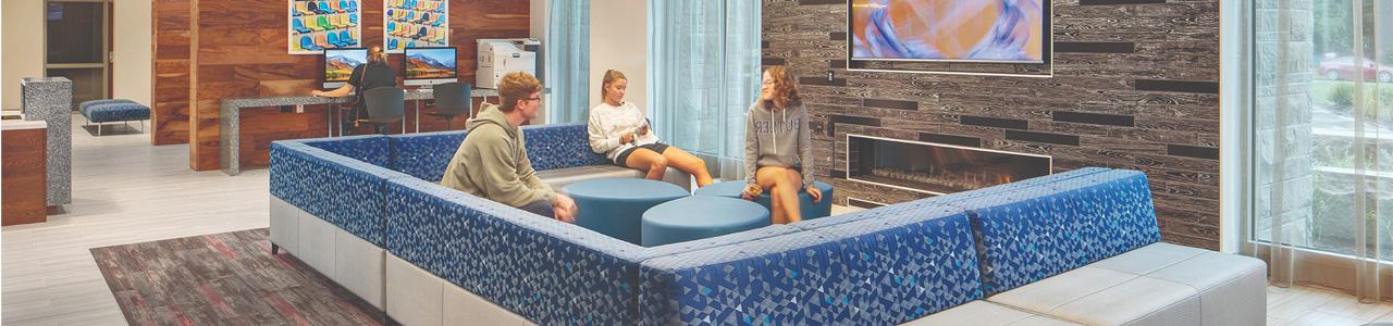 Students sit on couches inside a residence hall lobby